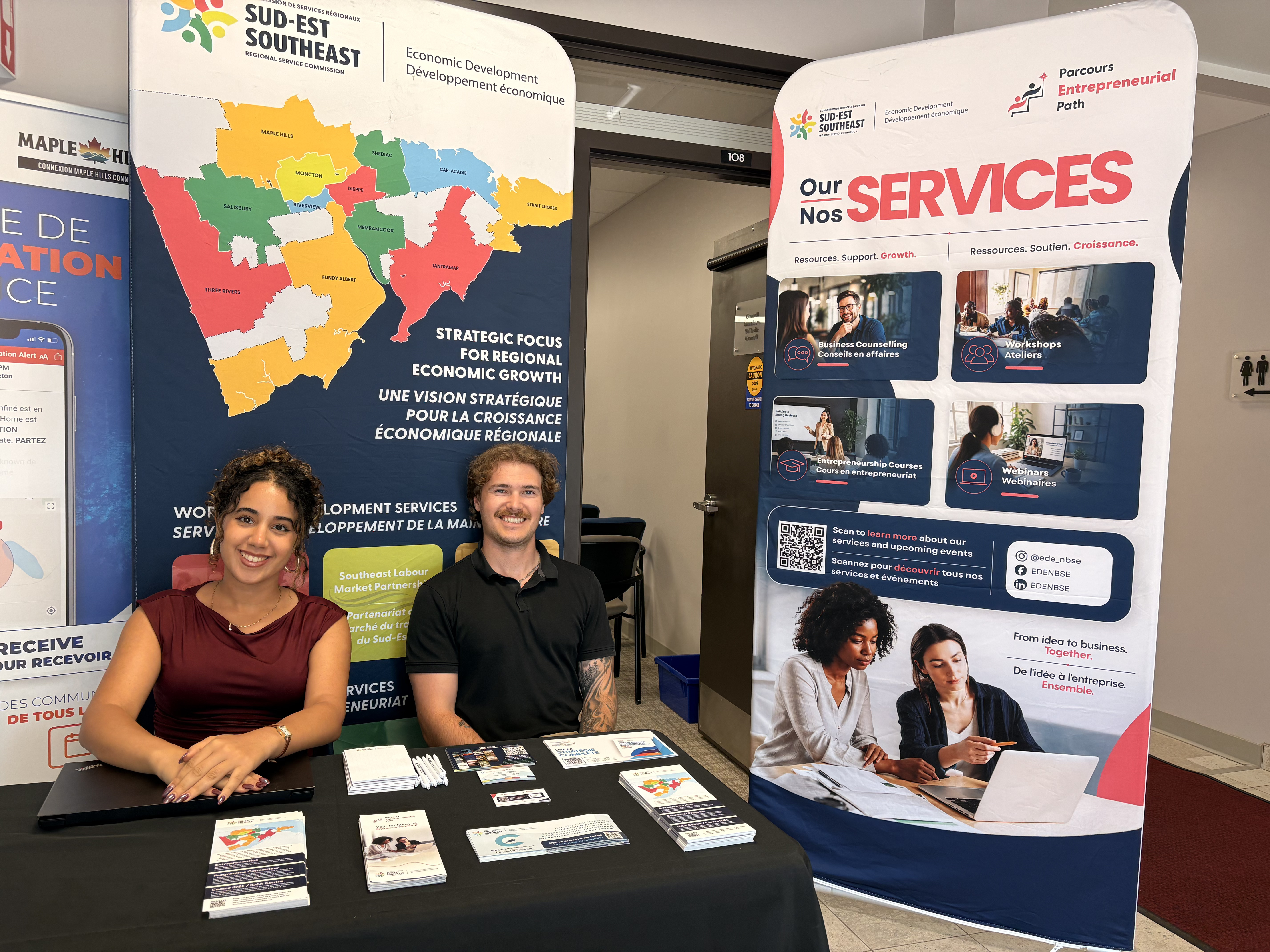 Two employees sitting at a kiosk with a banner showing the southeast region and another the services offered by Economic Development