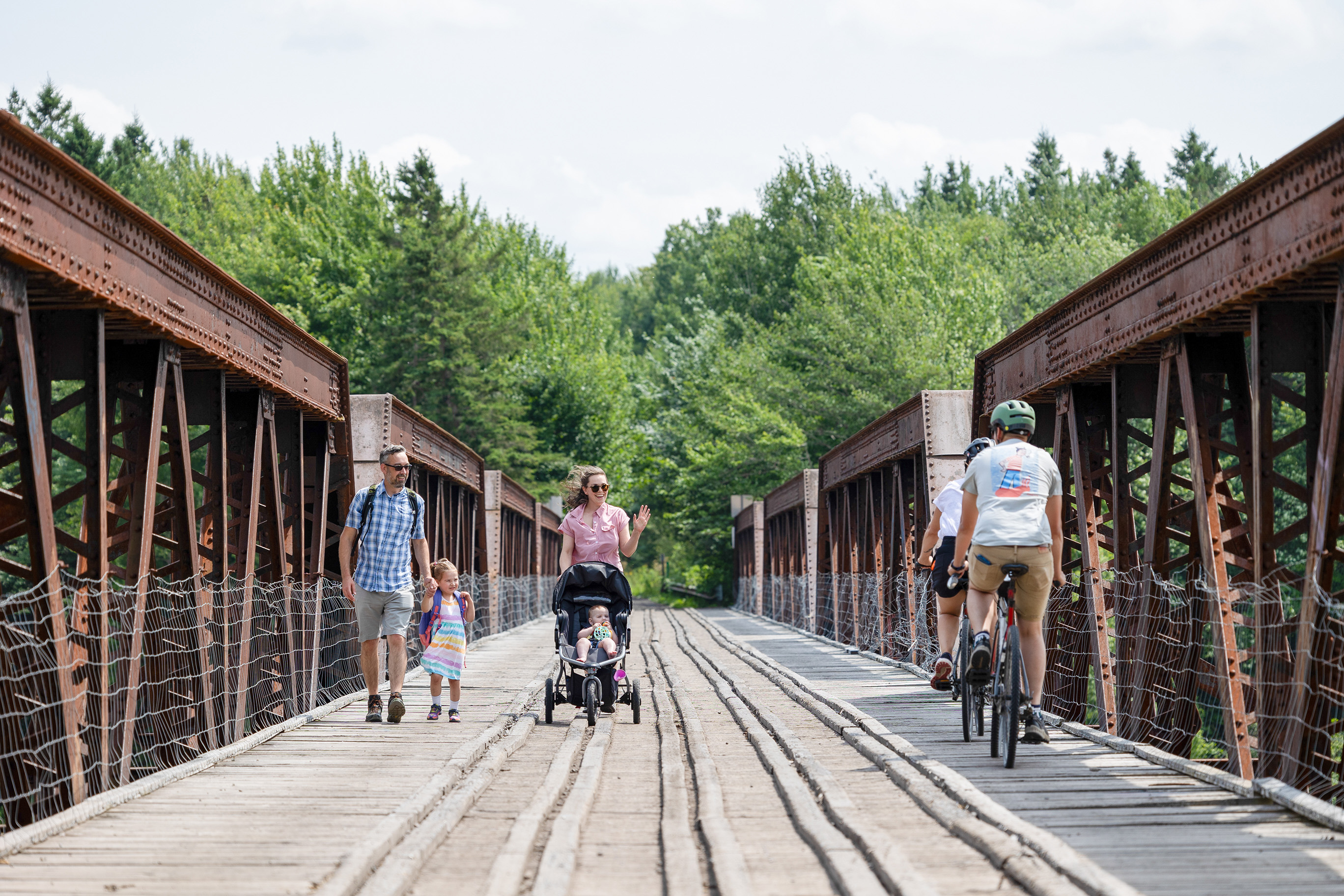 Des familles a pieds et en vélos traversent un pont sur le réseau de sentiers Odyssée